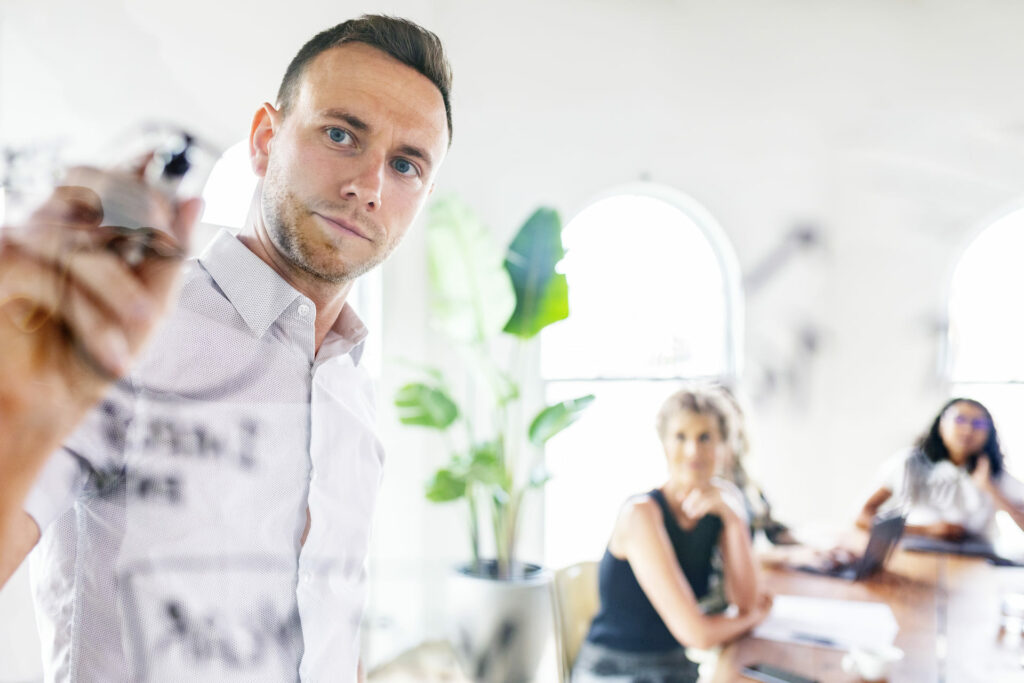 Mann schreibt auf gläserne Fläche beim Leadership Coaching